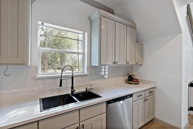 kitchen with baseboards, a sink, light countertops, dishwasher, and backsplash