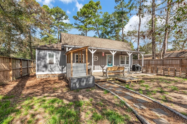 rear view of property featuring an outdoor structure, a fenced backyard, and roof with shingles