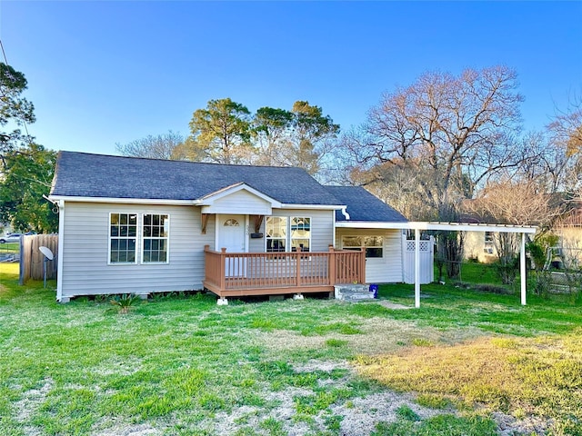 view of front of home featuring a wooden deck, a shingled roof, a front yard, and fence