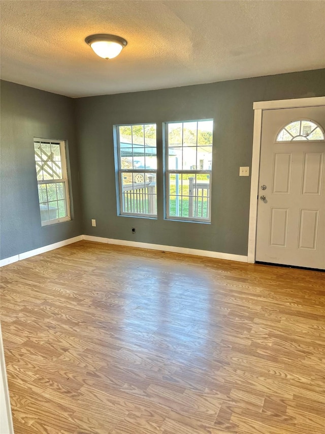 entrance foyer with baseboards, light wood-style floors, and a textured ceiling