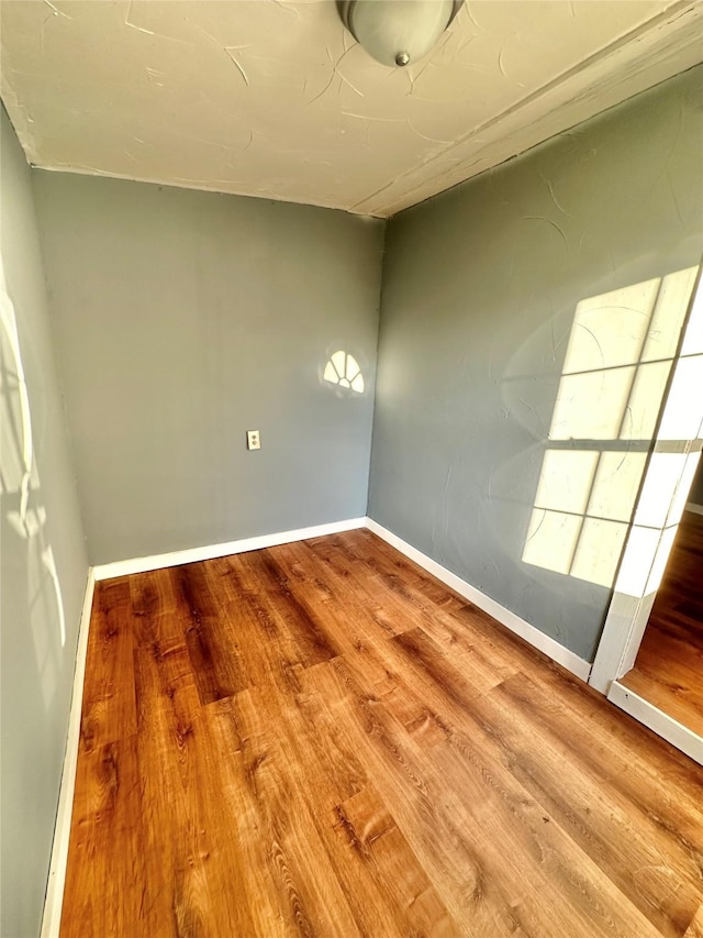 empty room featuring wood finished floors and baseboards