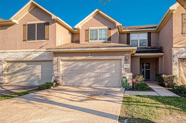 townhome / multi-family property featuring stucco siding, stone siding, and a garage