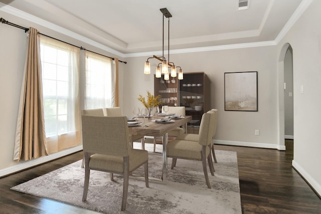 dining space with a tray ceiling, arched walkways, visible vents, and wood finished floors