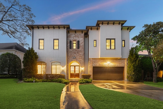 view of front of house featuring stucco siding, a lawn, driveway, an attached garage, and brick siding