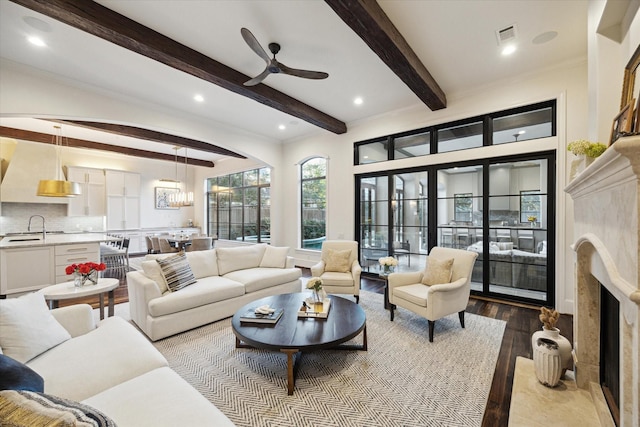 living area with beamed ceiling, wood finished floors, recessed lighting, a premium fireplace, and ceiling fan