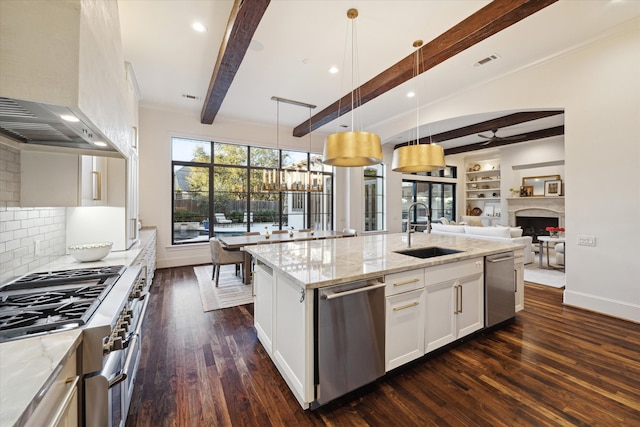 kitchen featuring light stone counters, a fireplace, a sink, dishwasher, and wall chimney exhaust hood