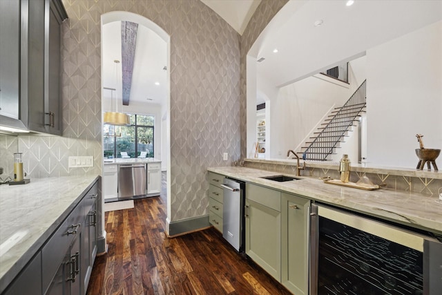 kitchen with dark wood-type flooring, beverage cooler, a sink, stainless steel dishwasher, and light stone countertops