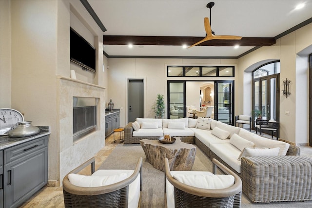 living area with beamed ceiling, arched walkways, ceiling fan, and a fireplace