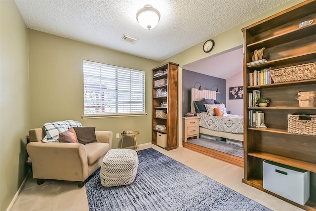 sitting room with baseboards, carpet, visible vents, and a textured ceiling