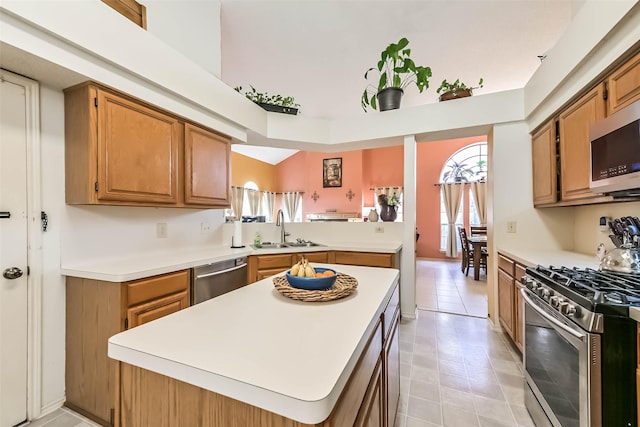 kitchen featuring a sink, a center island, appliances with stainless steel finishes, a peninsula, and light countertops