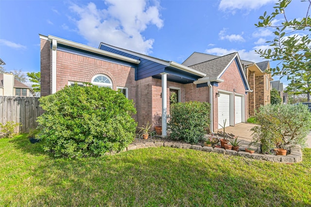 view of front of property with fence, concrete driveway, a front yard, a garage, and brick siding