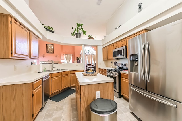 kitchen with light countertops, a kitchen island, appliances with stainless steel finishes, and a sink