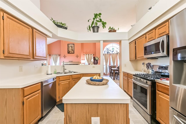 kitchen featuring appliances with stainless steel finishes, a center island, light countertops, and a sink