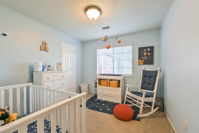 bedroom with visible vents, a textured ceiling, carpet floors, a nursery area, and baseboards