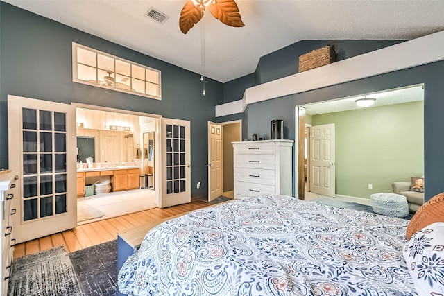 bedroom featuring baseboards, visible vents, high vaulted ceiling, light wood-style floors, and ensuite bathroom