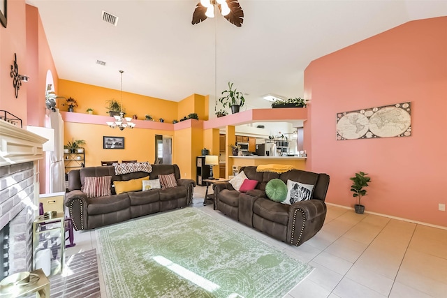 tiled living room with visible vents, a brick fireplace, baseboards, ceiling fan with notable chandelier, and high vaulted ceiling