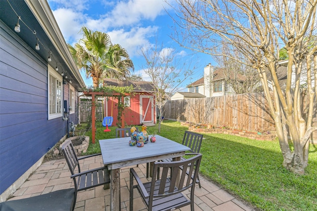 view of patio with an outbuilding, outdoor dining space, and a fenced backyard