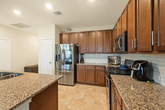 kitchen featuring visible vents, stainless steel appliances, decorative backsplash, and light stone countertops