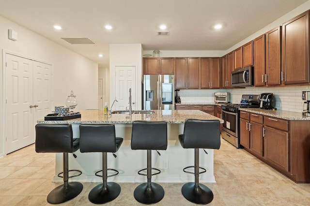 kitchen with stainless steel appliances, a kitchen breakfast bar, tasteful backsplash, and visible vents