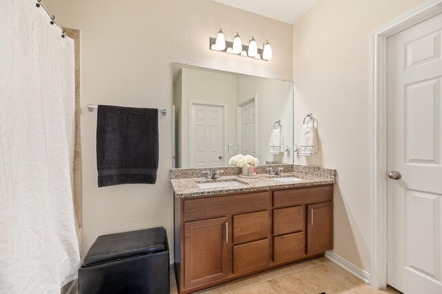 bathroom with a sink, curtained shower, double vanity, and tile patterned flooring