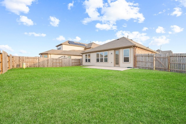 rear view of property featuring a yard, a patio, and a fenced backyard