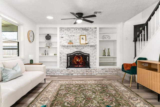 living area featuring visible vents, built in shelves, a textured ceiling, and a fireplace