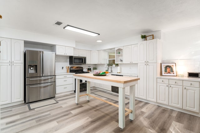 kitchen featuring white cabinetry, decorative backsplash, light wood-type flooring, and stainless steel appliances