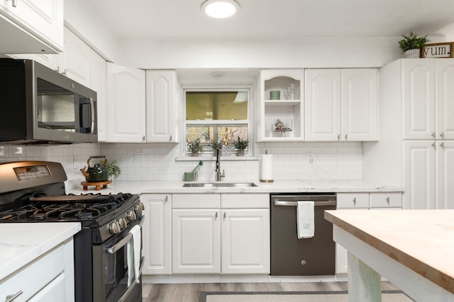 kitchen with backsplash, white cabinets, appliances with stainless steel finishes, and a sink