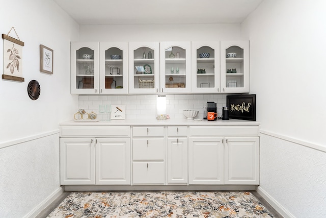 bar with a wainscoted wall, backsplash, and baseboards