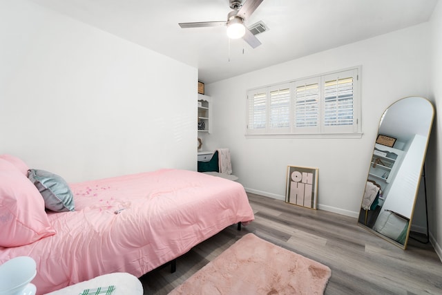 bedroom with ceiling fan, visible vents, baseboards, and wood finished floors