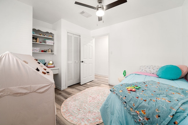 bedroom with a ceiling fan, visible vents, baseboards, light wood-style flooring, and a closet