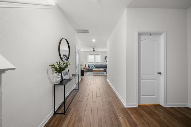 hallway featuring baseboards, visible vents, and dark wood-style flooring