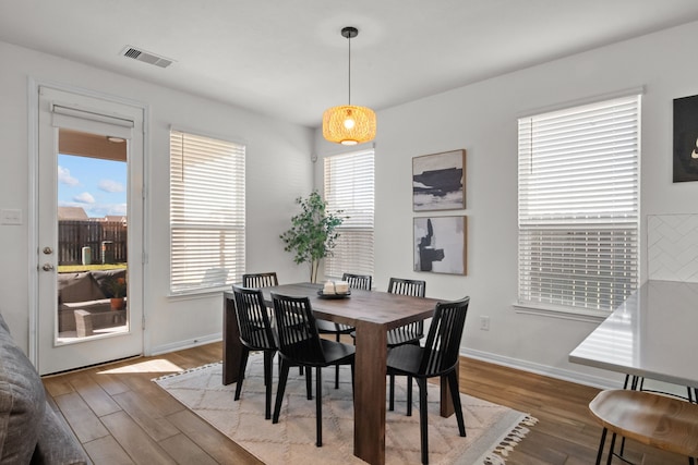 dining area featuring visible vents, baseboards, and wood finished floors