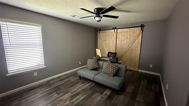 sitting room featuring visible vents, ceiling fan, baseboards, a barn door, and wood finished floors