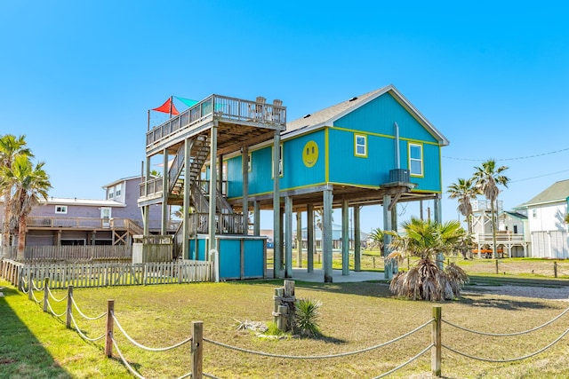 back of property with a carport, a lawn, stairs, and fence