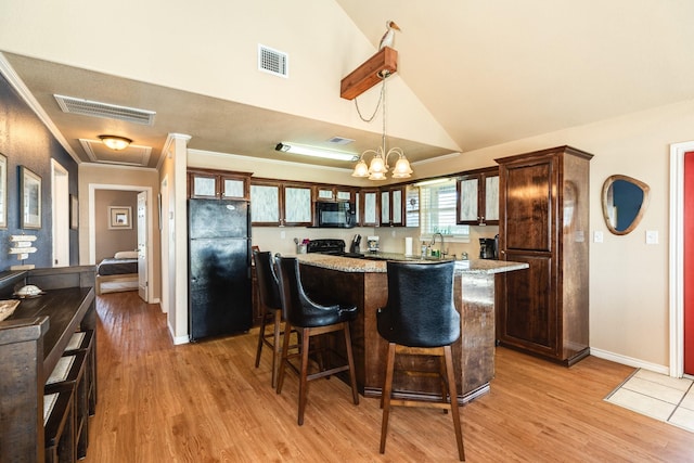 kitchen with visible vents, a notable chandelier, black appliances, a breakfast bar, and a kitchen island