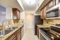 kitchen featuring light countertops, tasteful backsplash, appliances with stainless steel finishes, and a sink