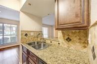 kitchen featuring light stone counters, decorative backsplash, and a sink