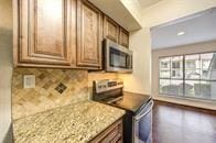 kitchen with tasteful backsplash, stainless steel appliances, and brown cabinetry