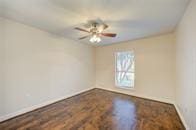 spare room with a ceiling fan, wood finished floors, and baseboards