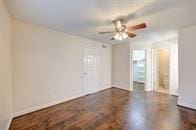 unfurnished room with baseboards, a ceiling fan, and dark wood-style flooring