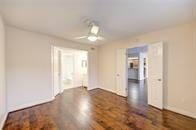 spare room with baseboards, ceiling fan, and dark wood-style flooring