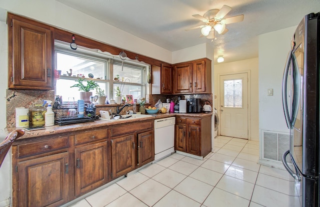 kitchen featuring visible vents, a sink, freestanding refrigerator, white dishwasher, and light tile patterned floors