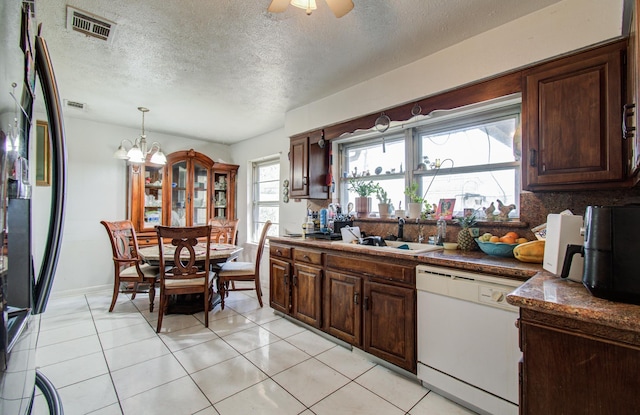 kitchen featuring visible vents, a sink, dark countertops, white dishwasher, and dark brown cabinets