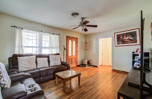 living room with light wood-type flooring, visible vents, baseboards, and a ceiling fan