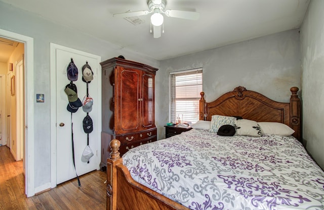 bedroom with wood finished floors, visible vents, and ceiling fan