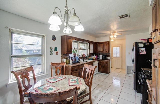 dining space with light tile patterned floors, visible vents, a textured ceiling, and ceiling fan with notable chandelier