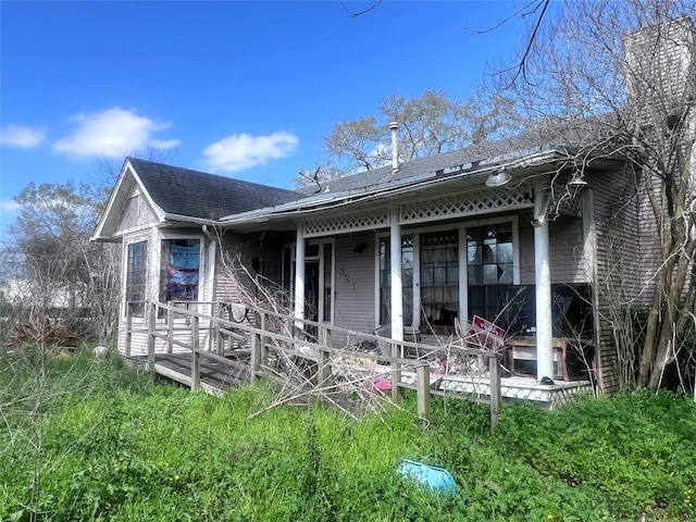 rear view of house featuring roof with shingles