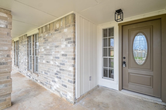 doorway to property with brick siding and a porch