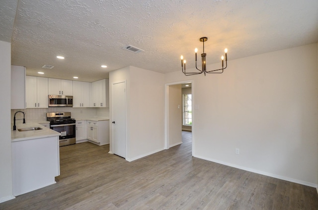 kitchen with appliances with stainless steel finishes, wood finished floors, light countertops, and a sink